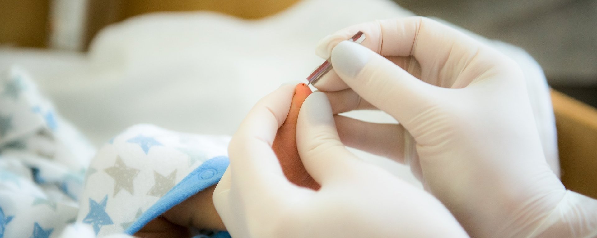 Ein Doktor nimmt Blut am Fuß eines Neugeborenen ab.